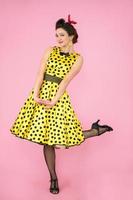Retro girl. Beautiful woman in a dress with polka dots on heels on a bright background. photo