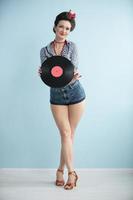 Retro girl with a vinyl record on a blue background. photo