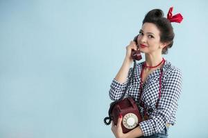 Woman in the style of the fifties. Beautiful retro woman with a dial phone. photo