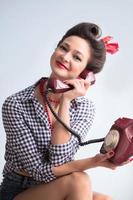 Woman in the style of the fifties. Beautiful retro girl with an old telephone. photo