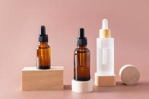 various cosmetic bottles with a dropper with an organic natural face care product stand on geometric wooden shapes. front view. photo