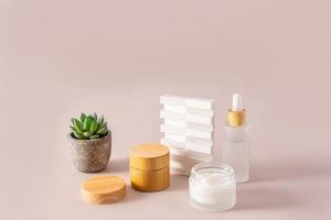 a set of cosmetics for the care of the skin of the face and body on a beige background. front view. eco cosmetics in matte bottles with bamboo lid. photo