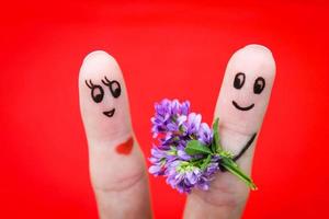 Face painted on fingers. Man is giving flowers to a woman. photo