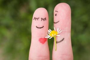 Face painted on fingers. Man is giving flowers to a woman. photo