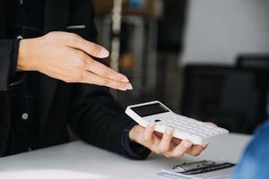 Closeup of Asian female signing car insurance document or lease paper contract or agreement. Buying or selling new or used vehicle with car keys on table. photo