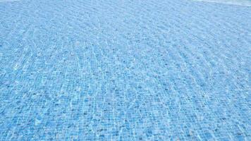 The wind makes water ripple. Sea water pool with stairs for relaxing. Blue clear water surface in swimming pool. Summer Vacation and rest concept. Pattern of bottom made of mosaic ceramic blue tiles. video