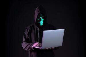 a hacker in a hoodie using a laptop computer isolated on dark background with neon light. photo