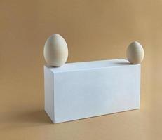 Wooden easter egg for painting on white podium on a pastel background. Scene with geometrical forms. Copy space. photo