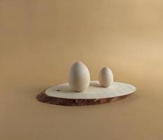 Wooden easter egg for painting on a wooden podium on a pastel background. Scene with geometrical forms. Copy space. photo