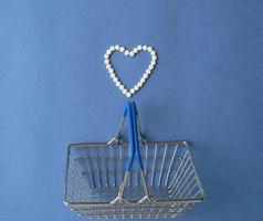 Shopping basket and Heart symbol made from pills on blue background. Treatment of heart disease and of hope for recovery. Creative idea for online pharmacy and pharmaceutical company business concept. photo