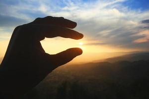 hermosa silueta mano participación en Dom y puesta de sol en el montaña. poder y esperanza concepto. foto