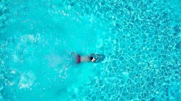 Aussicht von das oben wie ein Mann Springen und Tauchgänge in das Schwimmbad und schwimmt unter das Wasser video