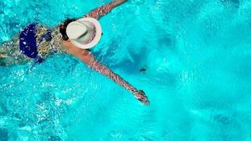 visie van de top net zo een vrouw in een blauw zwempak zwemt in de zwembad video
