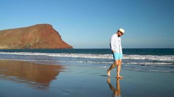 Happy man walking along the ocean beach at sunset. Concept of carefree modern life. Tenerife, Canarian Islands, Spain video