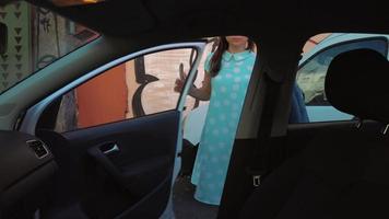 Woman put a jacket on the car seat and sits down on the driver's seat, intending to start the engine video