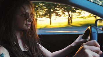 hermosa alegre mujer conducción un auto, hermosa paisaje y puesta de sol fuera de video