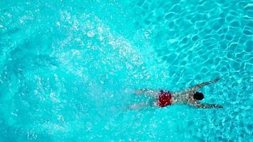 View from the top as a man jumping and dives into the pool and swims under the water video