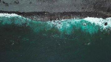 oben Aussicht von ein verlassen schwarz vulkanisch Strand. Küste von das Insel von Teneriffa. Antenne Drohne Aufnahmen von Meer Wellen erreichen video