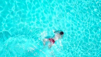 Aussicht von das oben wie ein Mann Springen und Tauchgänge in das Schwimmbad und schwimmt unter das Wasser video