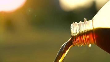 Cola flows from a plastic bottle against a background of natural greenery video