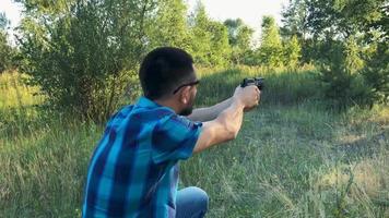 joven hombre con un pistola es puntería a disparar un cerca arriba video