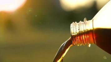 Cola flows from a plastic bottle against a background of natural greenery video