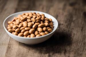 Almond nuts in white bowl on wooden table. Healthy snack. photo