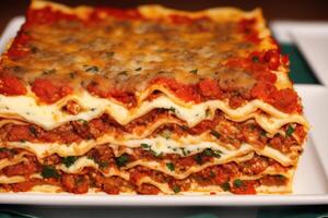 A stack of lasagna with a slice of lasagna on top on a wooden table. photo