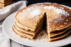 Stack of pancakes with maple syrup and sugar powder on a white plate. strawberries and whipped cream, photo