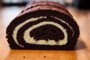 A swiss roll on a white plate on a wooden table. Homemade chocolate roll. Red velvet cake. photo