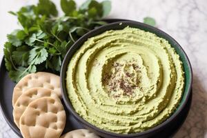 A bowl of hummus sits on a wooden table. photo