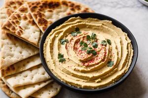 A bowl of hummus sits on a wooden table. photo