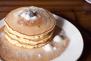 Stack of pancakes with maple syrup and sugar powder on a white plate. strawberries and whipped cream, photo