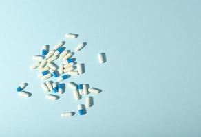 Randomly scattered pills. White and blue pills on blue background. Place for text. photo