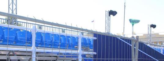 Empty grandstand with blue and white seats outdoors. photo