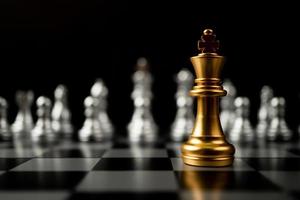 ajedrez rey dorado parado frente a otro ajedrez, el concepto de un líder debe tener coraje y desafío en la competencia, liderazgo y visión empresarial para ganar en los juegos de negocios foto