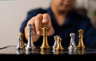 Close up of hands of a business man moving king golden chess to defeat opponent the chess game is development analysis, strategy, and plan, the management or leadership concept. photo