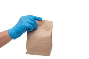 Close up hand in medical glove and holding food paper bag on white background  Isolated background. Concept of Ordering food online and delivery service. photo