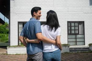 Happy couple in front of the New Home On Moving In Day, and start a new life family. Concept of homeowner and relocation photo