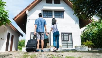 Happy couple in front of the New Home On Moving In Day, and start a new life family. Concept of homeowner and relocation photo