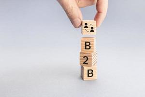 Business to Business B2B concept. Hand putting a block with icon and text word on top of others. Copy space photo