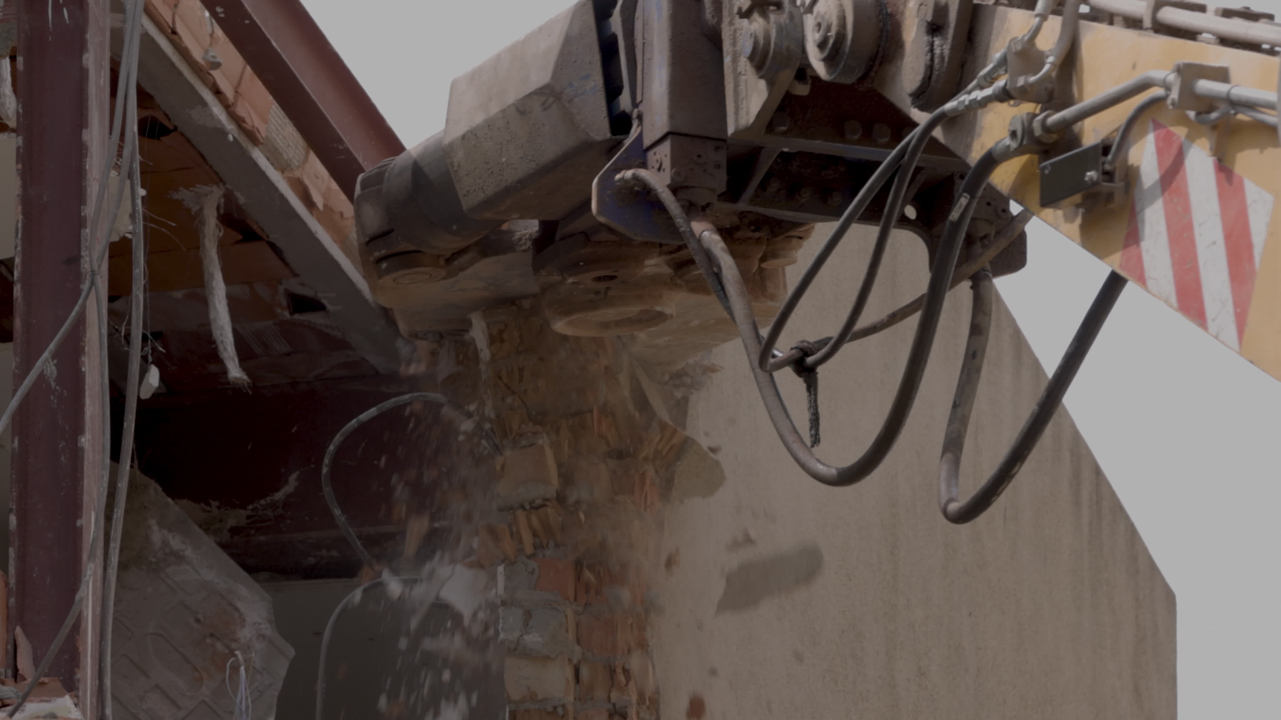 mechanical jaws on the end of a crane tear down an old building in slow