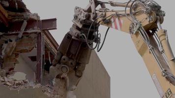 mechanical jaws on the end of a crane tear down an old building in slow motion video