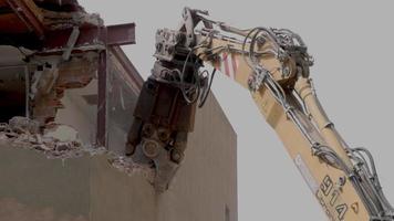 mechanical jaws on the end of a crane tear down an old building in slow motion video