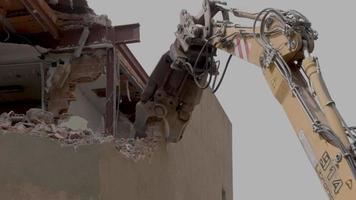 mechanical jaws on the end of a crane tear down an old building in slow motion video