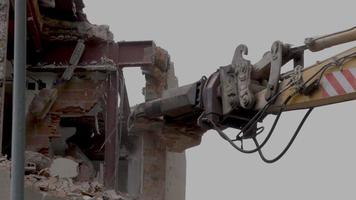 mechanical jaws on the end of a crane tear down an old building in slow motion video