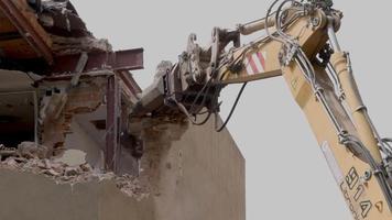 mechanical jaws on the end of a crane tear down an old building in slow motion video