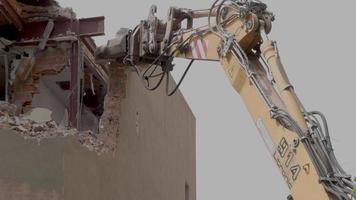 mecánico mandíbulas en el final de un grua lágrima abajo un antiguo edificio en lento movimiento video