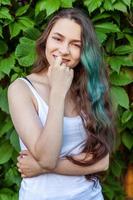 Beautiful young hipster brunete girl with long green hair smiling on park background photo