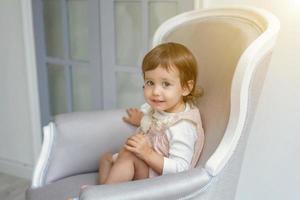 Little girl sitting on modern chair photo